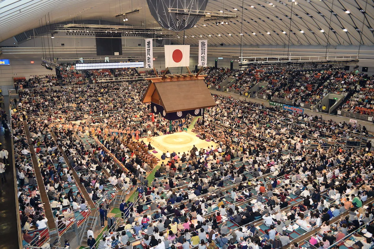 A packed sumo arena in Japan with the dohyo ring at the center